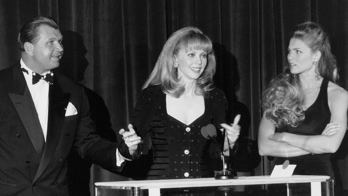 Kim Alexis standing to two castmates from "Cheers."