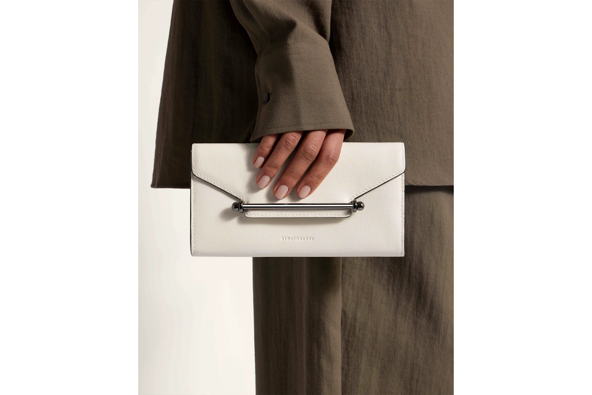 A model holding a Strathberry chain wallet