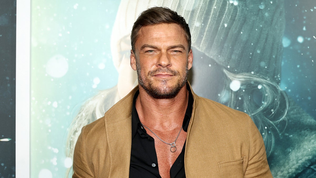 Alan Ritchson standing on a red carpet at the "Ordinary Angels" New York Premiere.