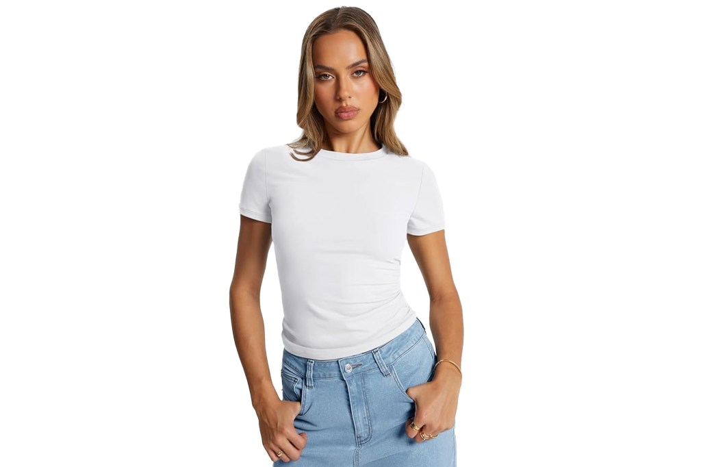 A woman models a white short-sleeved t-shirt and light wash jeans.
