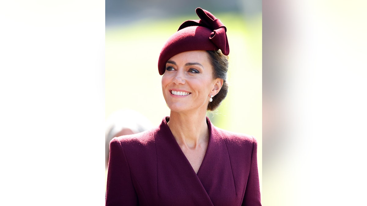 Kate Middleton wearing a dark purple suit smiling at Balmoral.