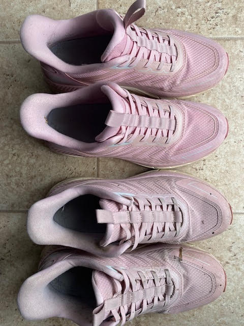 Two pairs of well-worn pink sneakers.