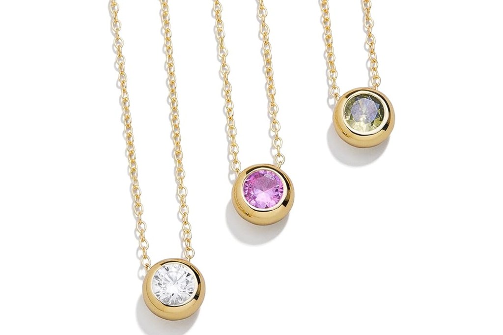 Three gold chain necklaces with bezel-set stones, a clear diamond, a pink sapphire, and a light green peridot.