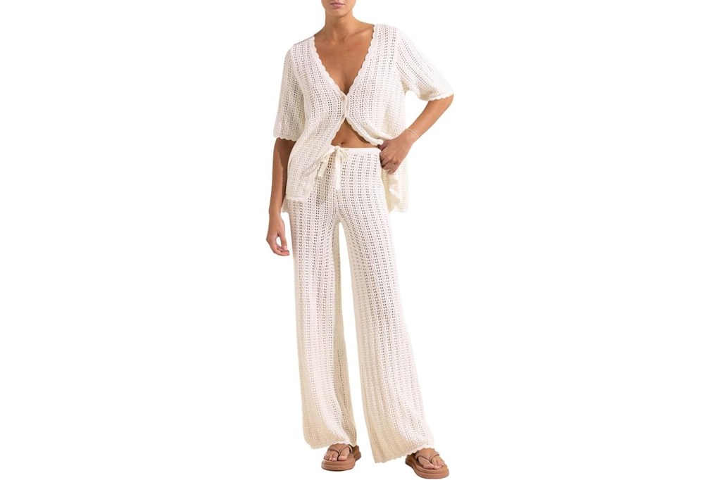 Model wearing a cream-colored crochet knit two-piece outfit with an open short-sleeved top and wide-leg pants.