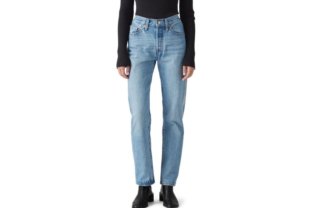Light blue high-waisted denim jeans with a button fly, worn with a black long-sleeved shirt and black ankle boots.