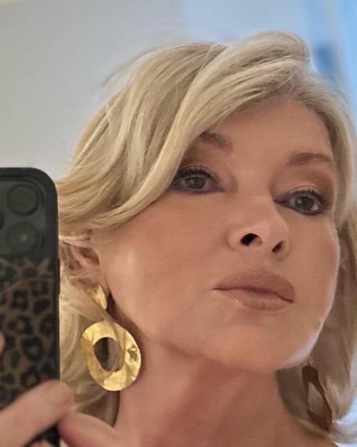 Martha Stewart taking a mirror selfie, showing off her makeup and large gold earrings.