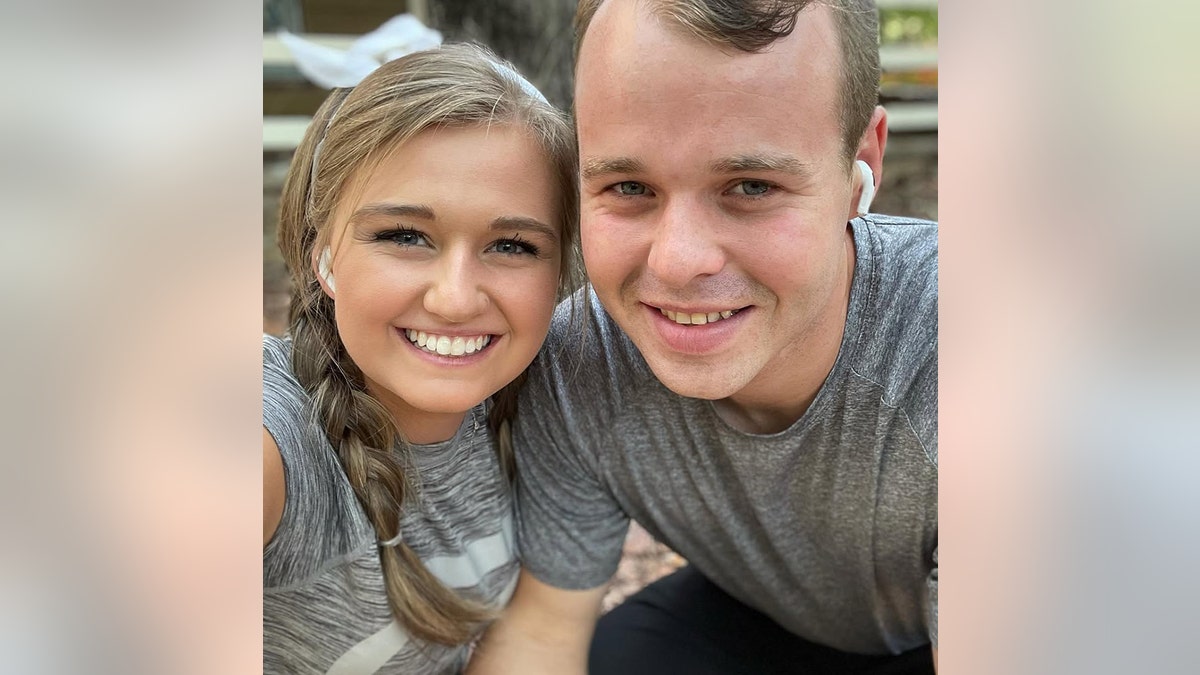 Joseph Duggar and his wife Kendra smiling and wearing matching grey shirts.