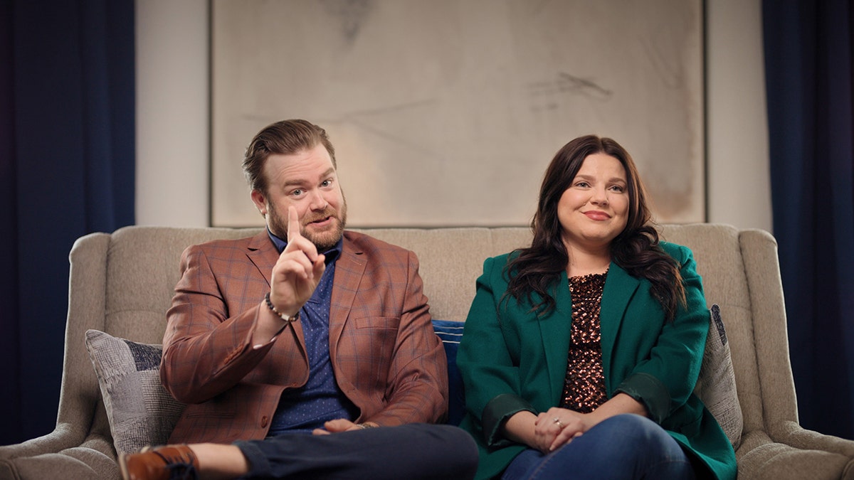 Amy Duggar King sitting and smiling next to her husband as they talk about the Duggar family.