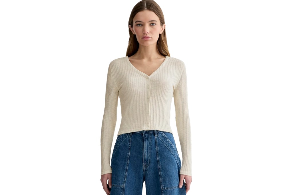 Woman wearing a cream ribbed button-up top and blue jeans.