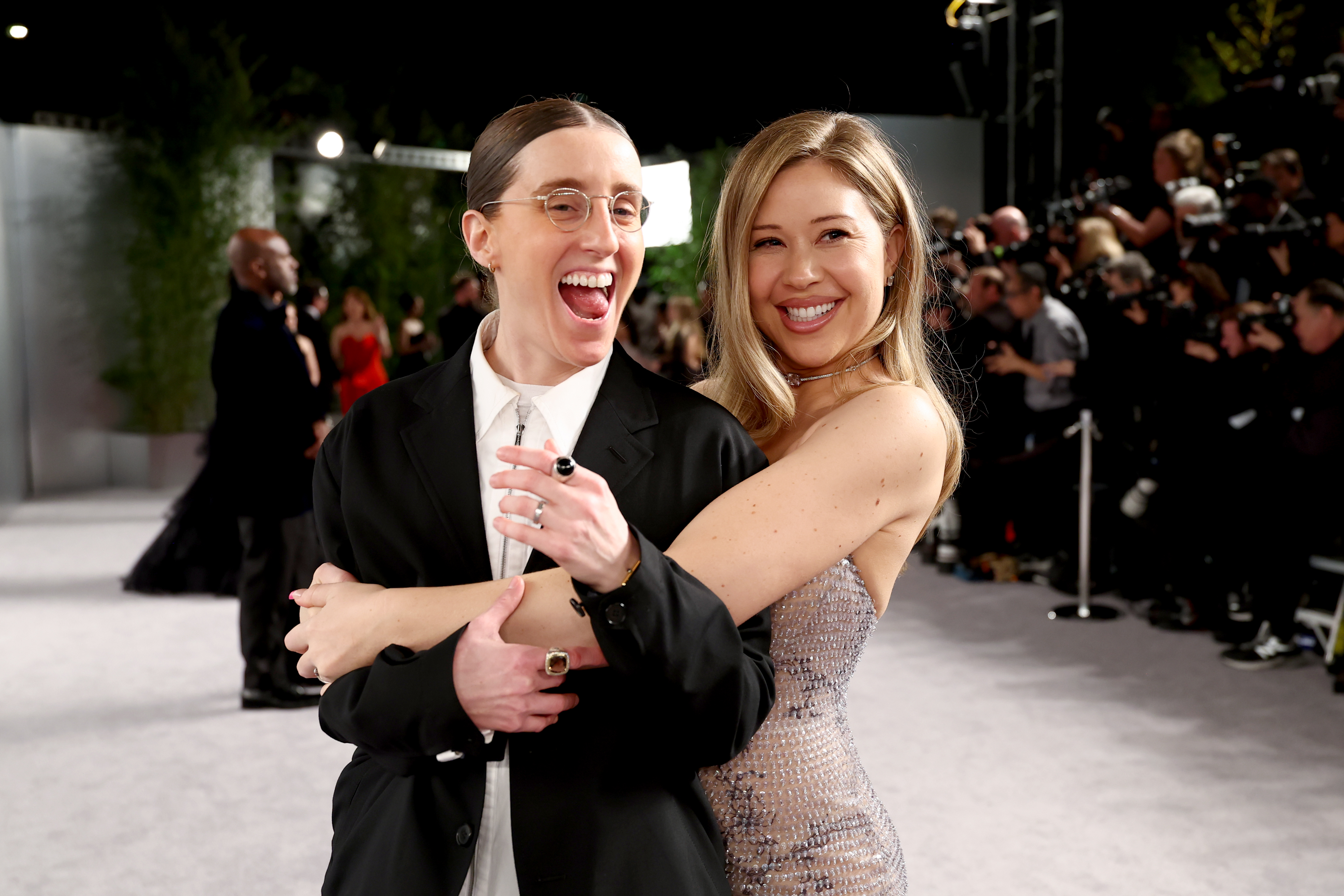 Robby Hoffman and Gabby Windey pose together, with Gabby holding Robby from behind, at the Vanity Fair Oscar Party.