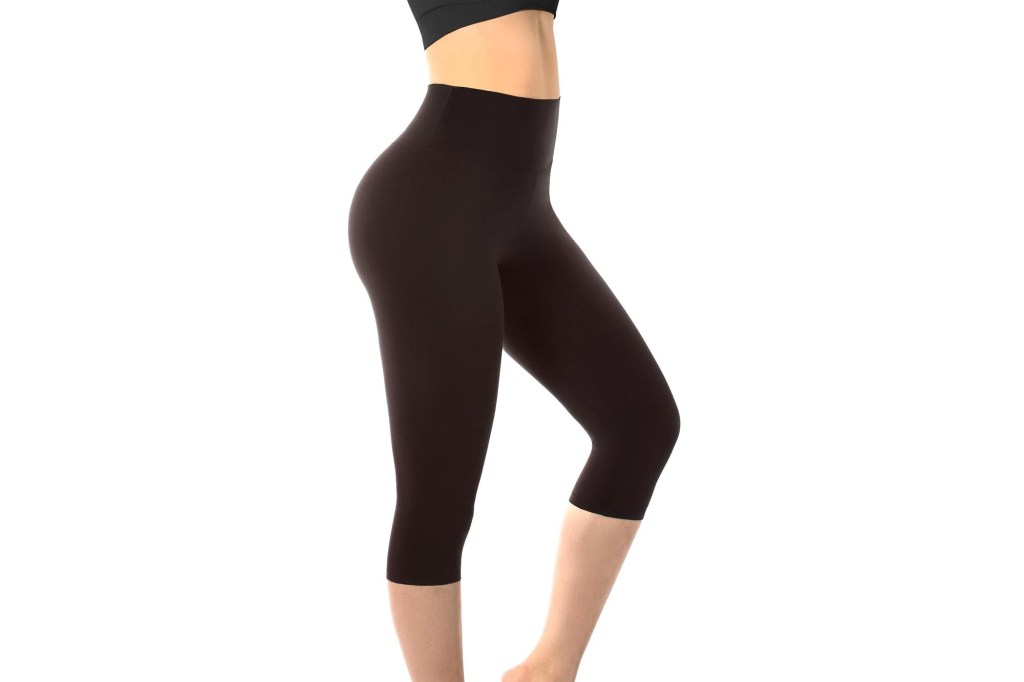 Side view of a person wearing black capri-length leggings with a high waistband and a black sports bra.