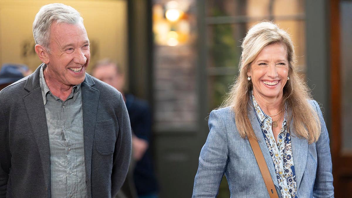 Tim Allen and Nancy Travis seated together on a television set
