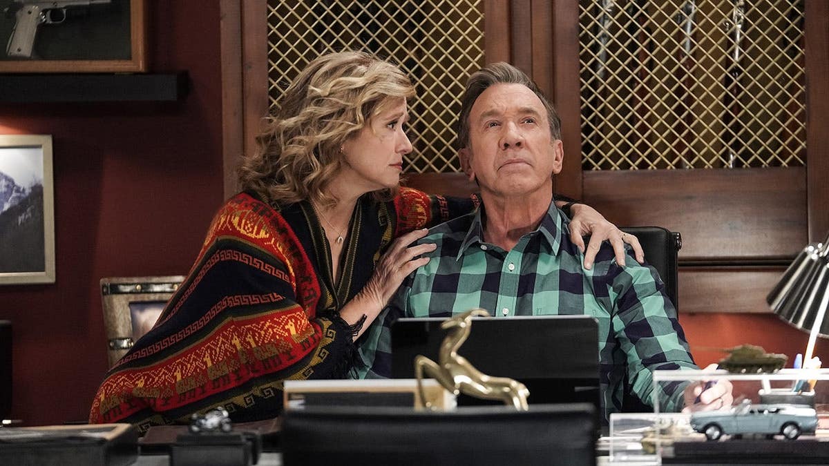 Nancy Travis and Tim Allen standing together on the set of Last Man Standing