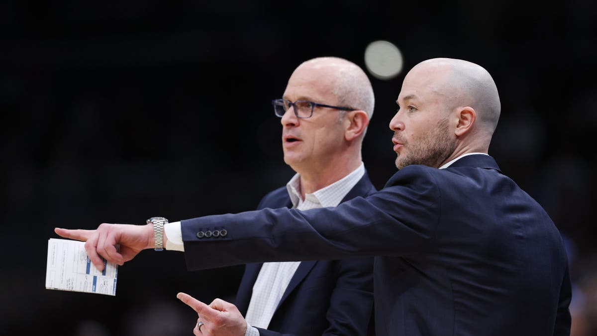 Assistant coach Luke Murray talking with head coach Dan Hurley during a basketball game.