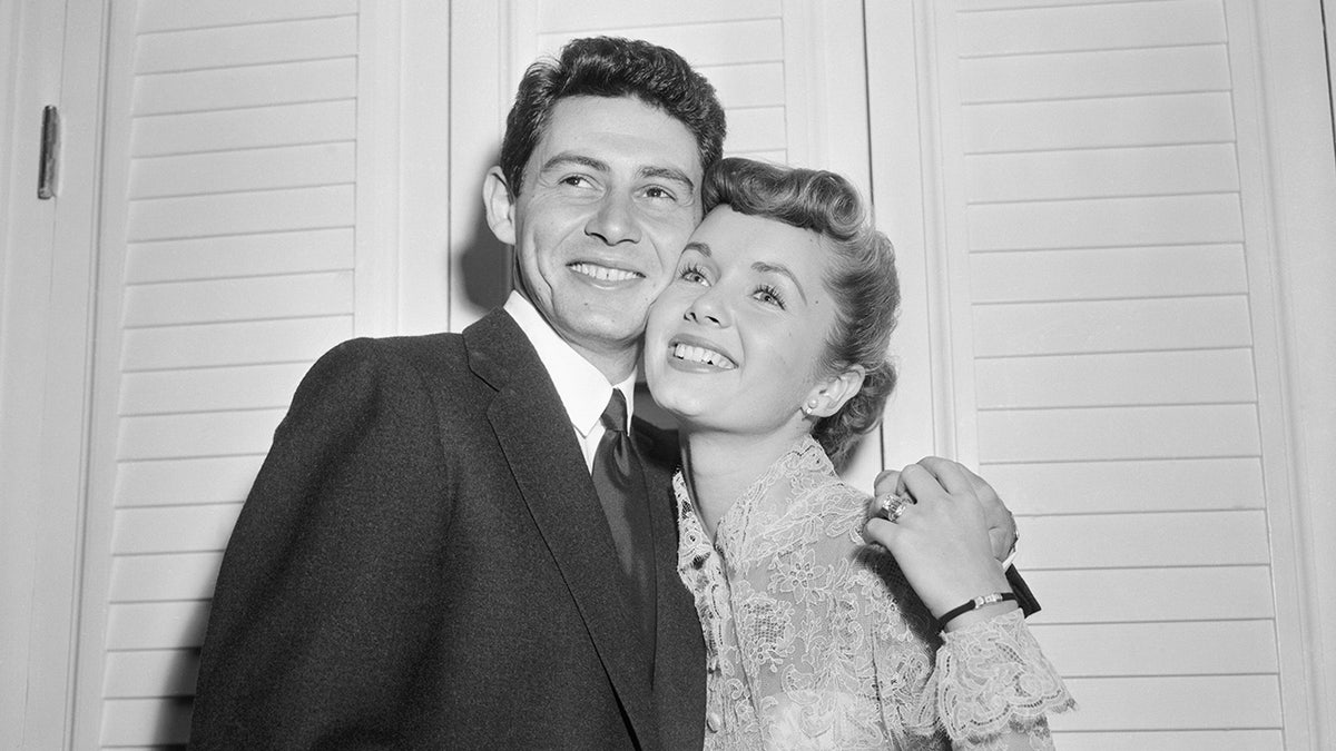 Actress Debbie Reynolds and fiancé Eddie Fisher smiling at a cocktail party