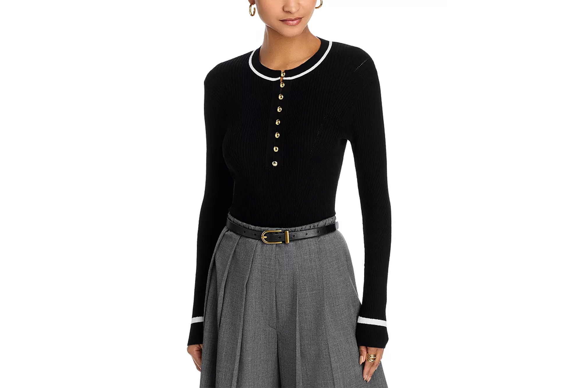 A model wearing a black ribbed long-sleeve top with white and gold trim, paired with grey pleated pants and a black belt.