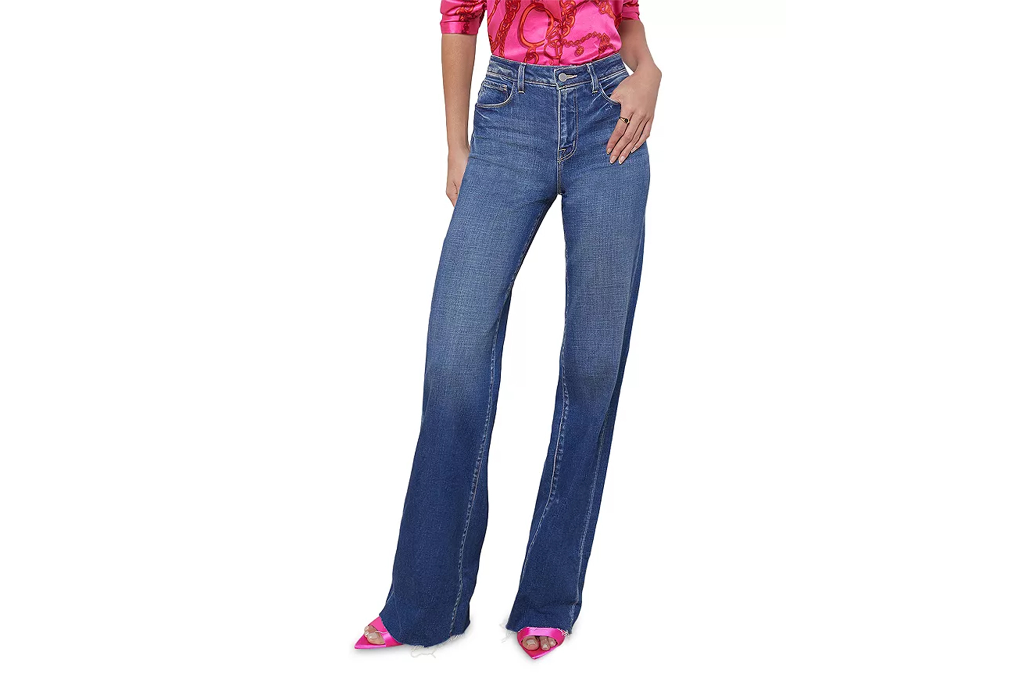L'Agence Jeans in a medium wash with flared legs, worn with a pink patterned blouse and pink high-heeled sandals.