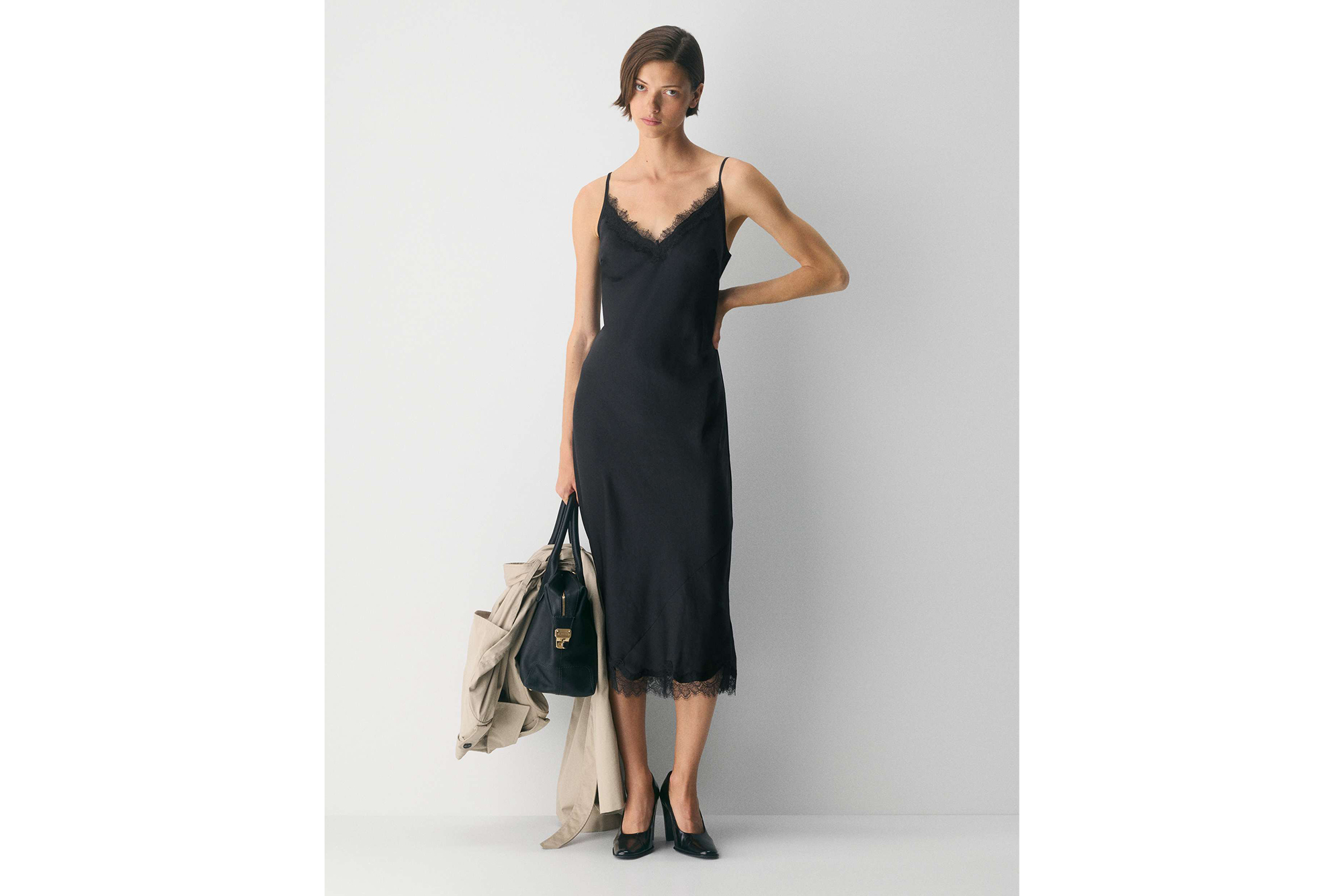 Model wearing the Aritzia Wilfred Lamplight Dress, a midi-length black slip dress with lace trim at the neckline and hem.