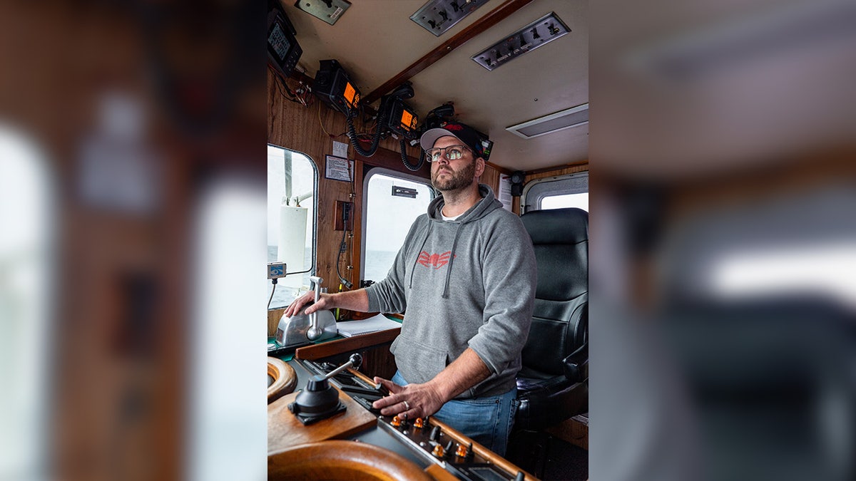 Captain Rick Shelford steering the Aleutian Lady boat wearing a grey sweatshirt