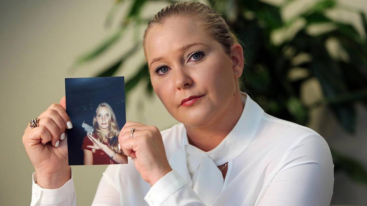 Virginia Giuffre holding a photo of herself as a teen