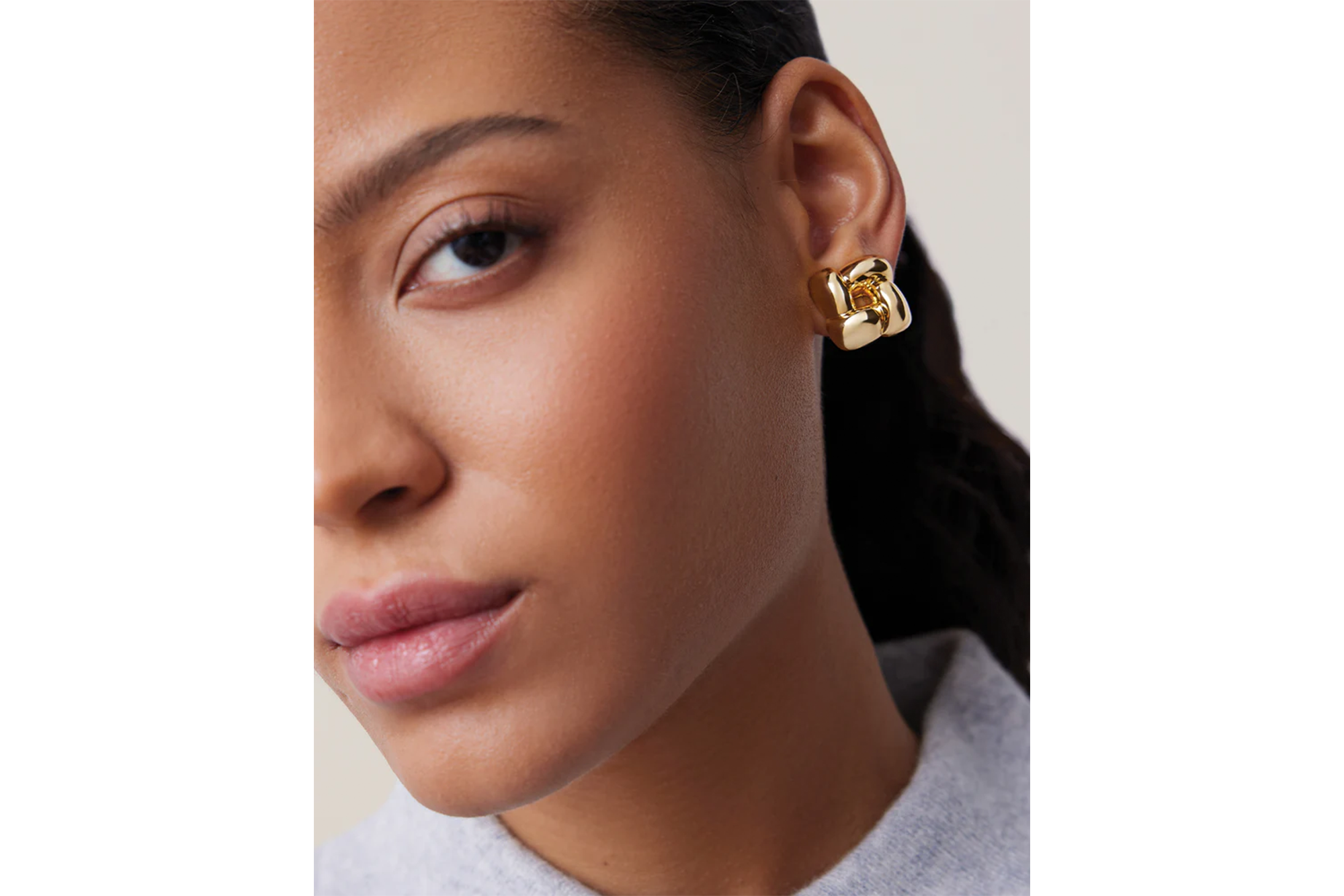 A woman wearing a gold knot earring.