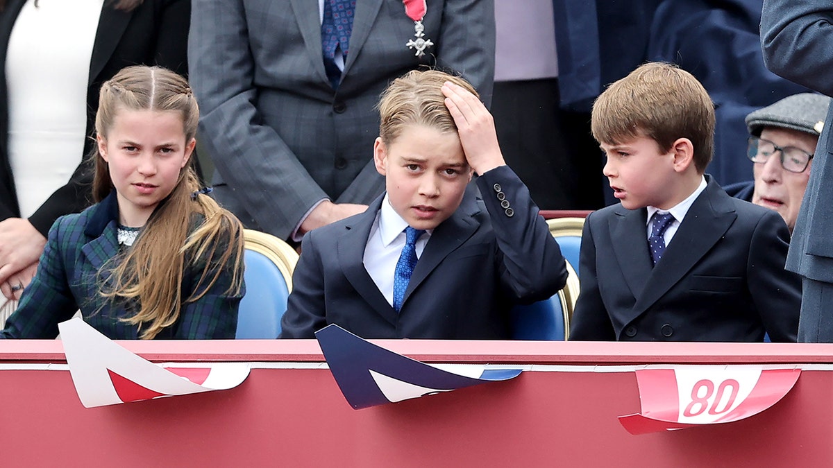 Princess Charlotte, Prince George of Wales and Prince Louis of Wales seated together in formal wear during a military procession in London