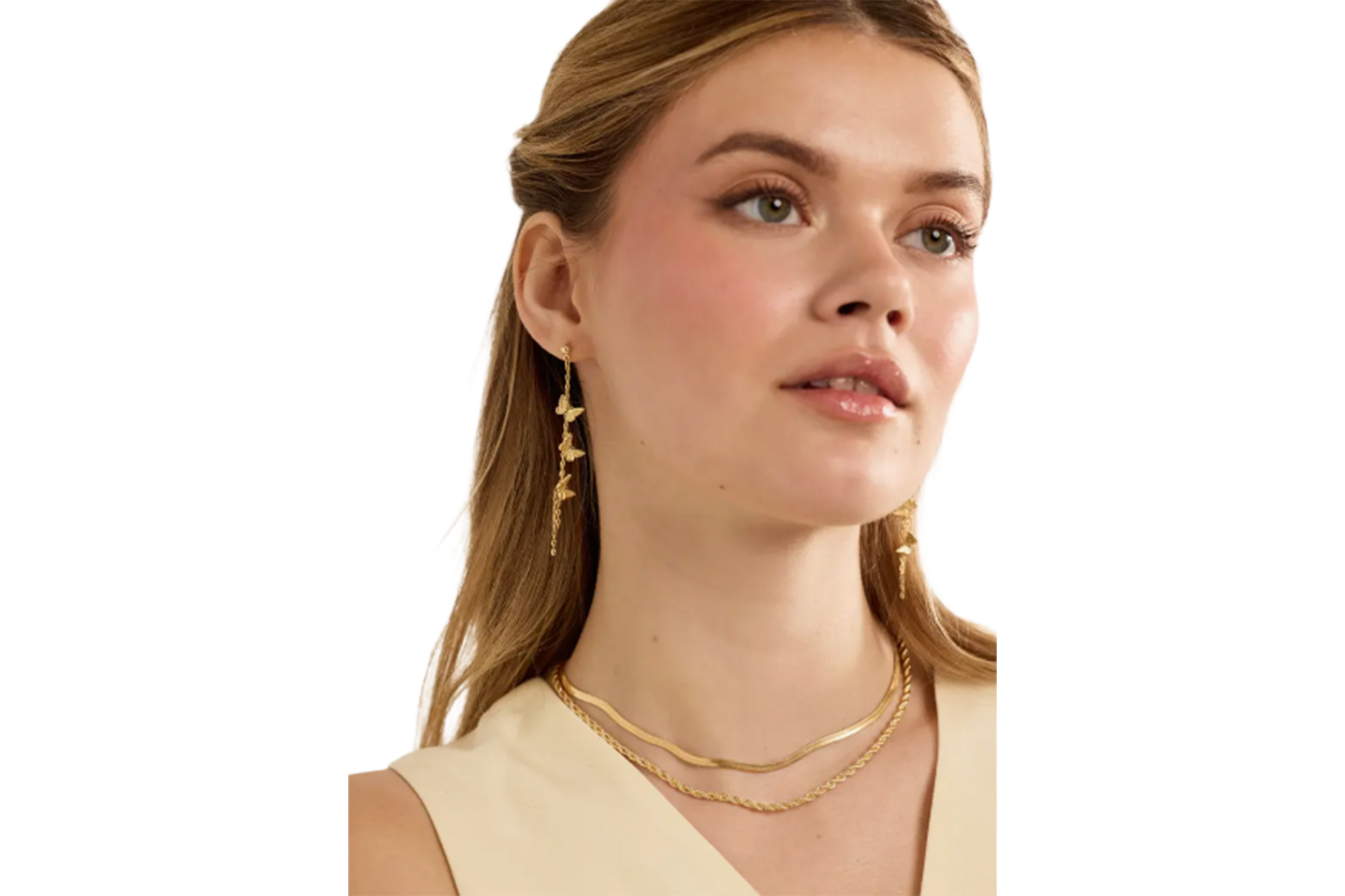 A young woman wearing gold butterfly earrings and two gold chain necklaces.