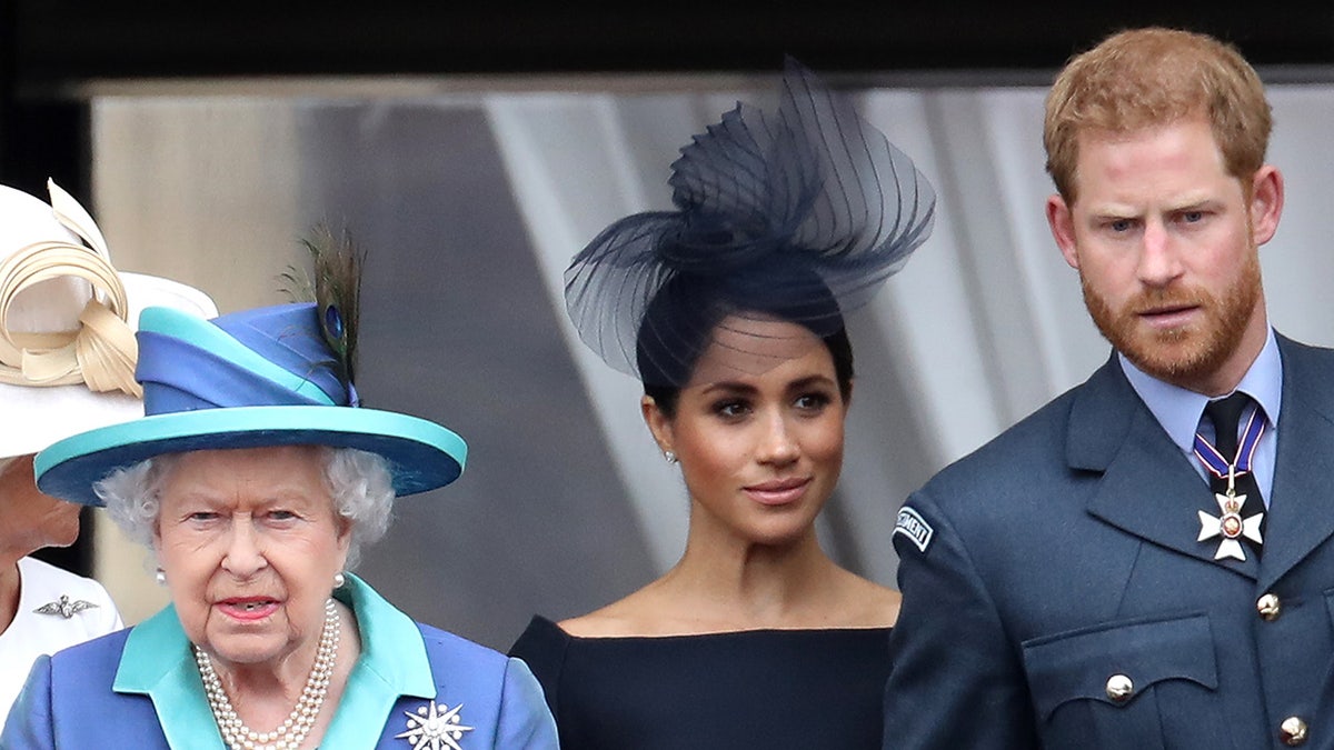 Queen Elizabeth II, Prince Harry, and Meghan Markle standing on Buckingham Palace balcony.