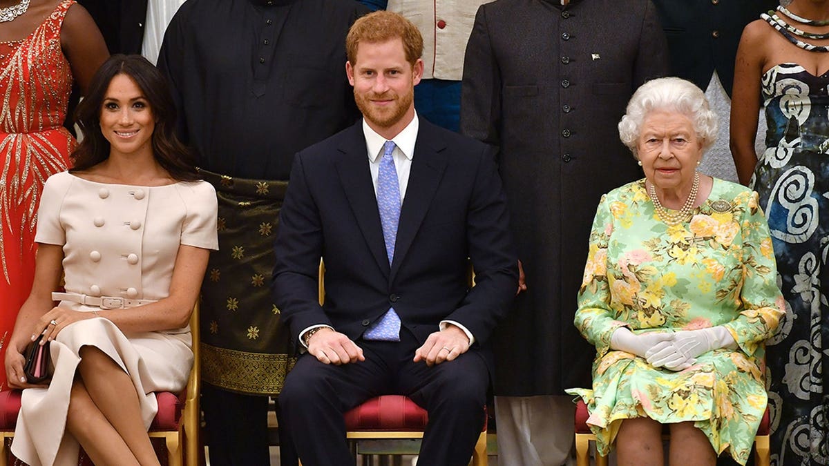 Meghan Duchess of Sussex Prince Harry and Queen Elizabeth II standing at Buckingham Palace