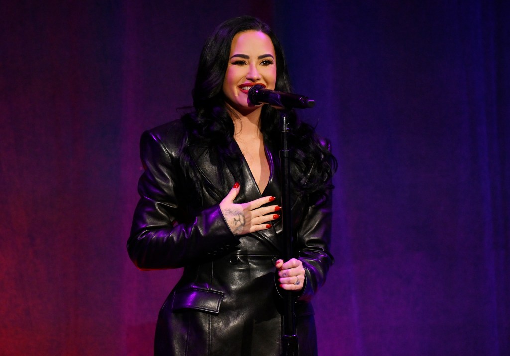 Demi Lovato singing into a microphone on stage.