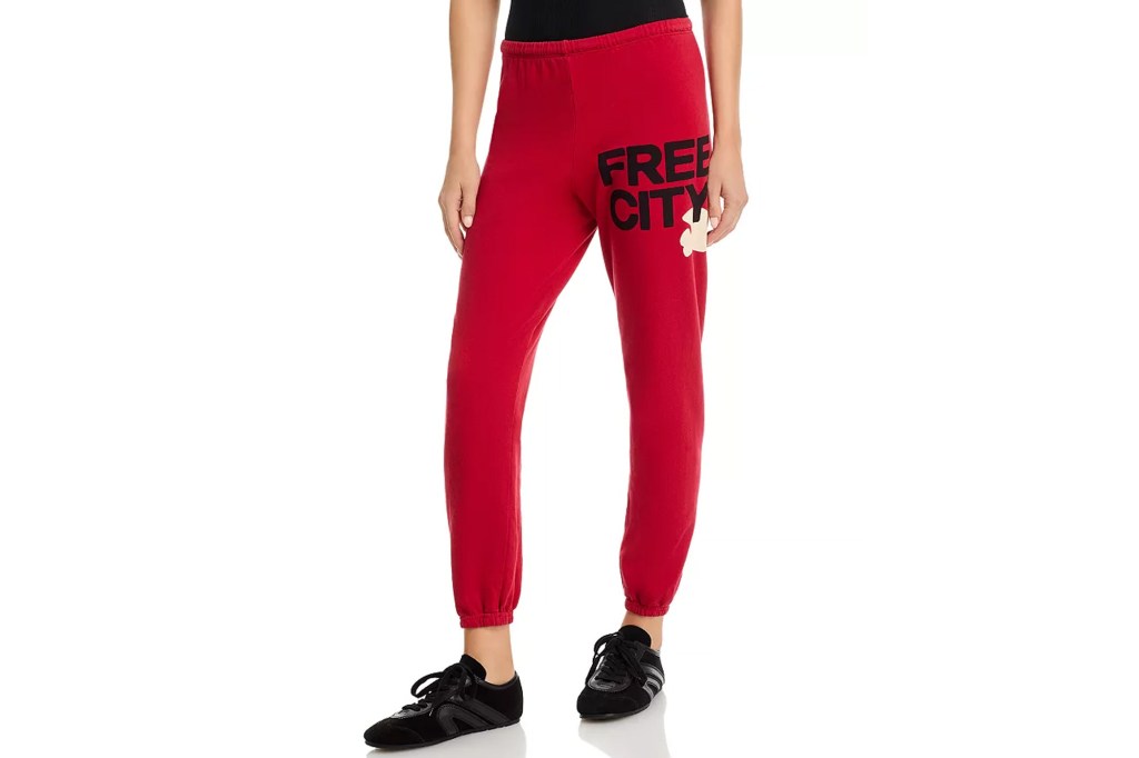 A person wearing red sweatpants with the text "FREE CITY" and a yellow bird graphic, paired with black sneakers.