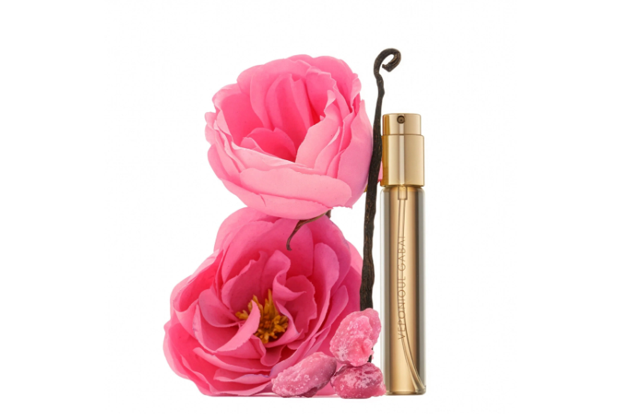 A gold perfume atomizer by Veronique Gabai next to two pink roses, a vanilla bean, and sugared pink almonds.