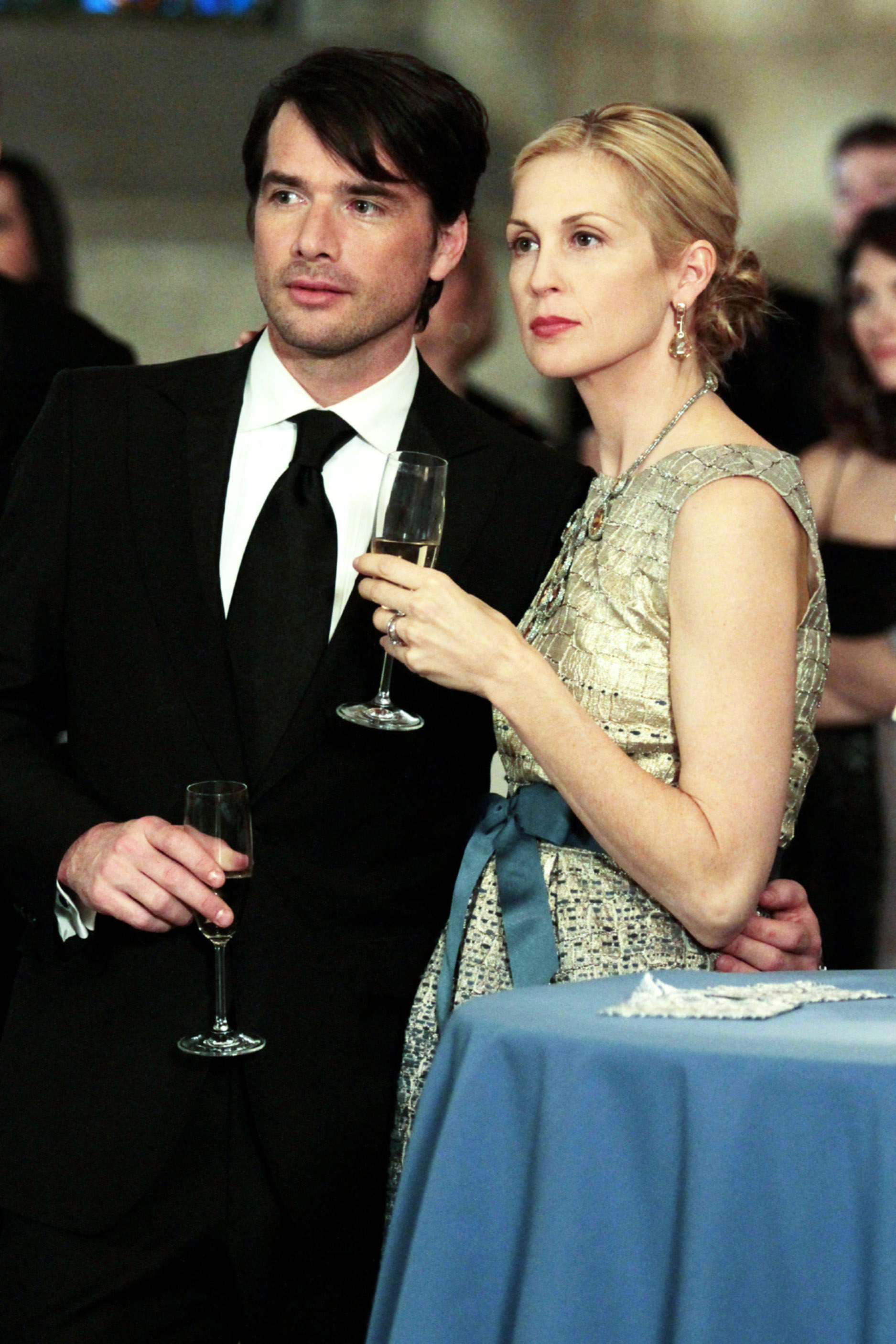 Matthew Settle and Kelly Rutherford holding champagne flutes.