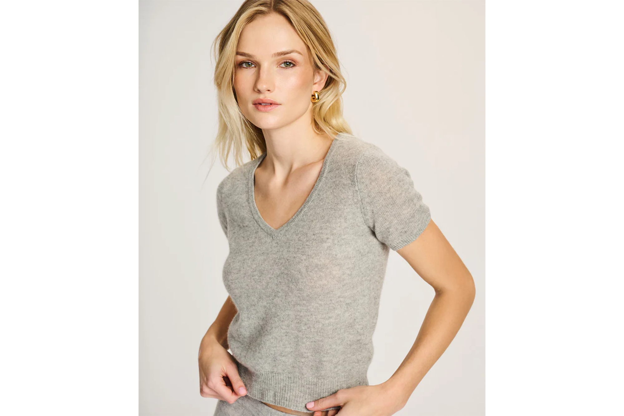 A woman wearing a light grey short-sleeved cashmere sweater.