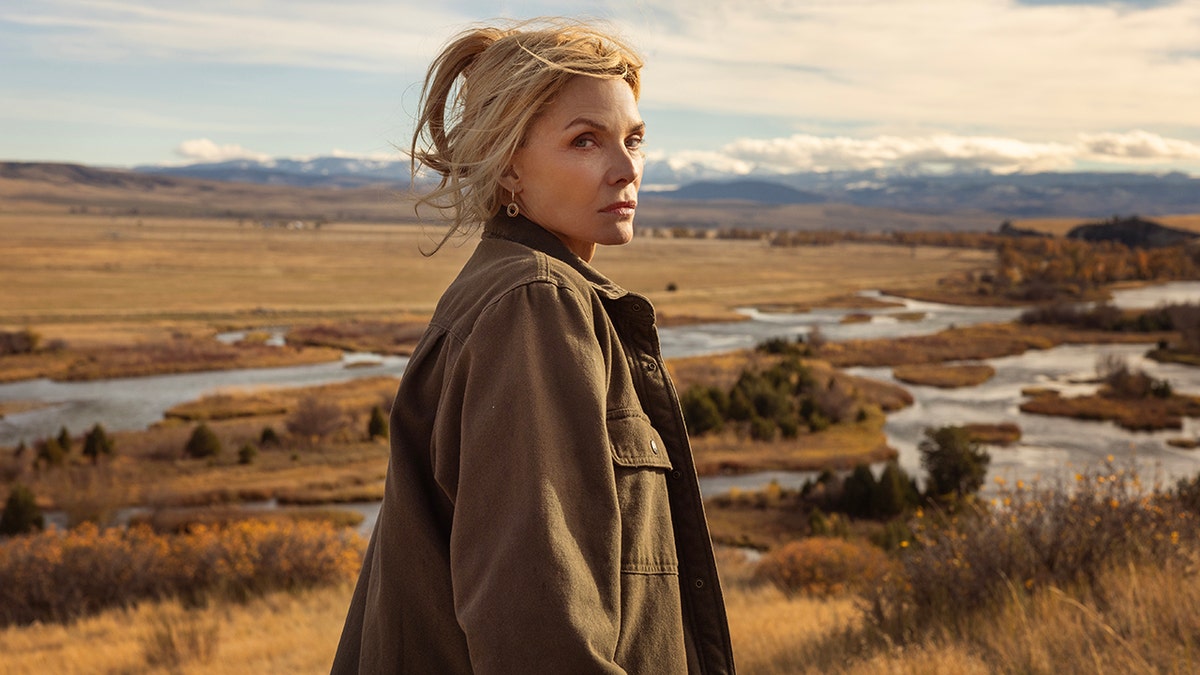 Michelle Pfeiffer as Stacy Clyburn standing on a hillside overlooking a valley