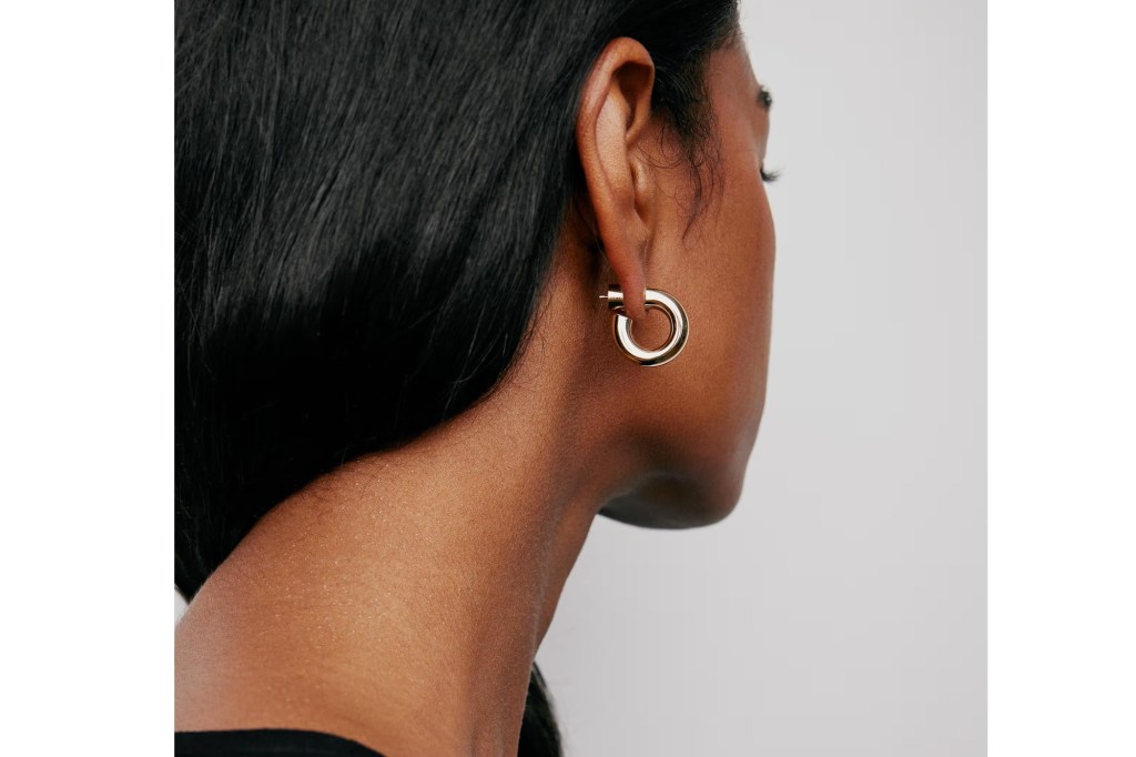 A woman with dark hair wears a gold hoop earring.