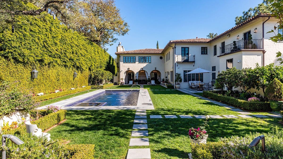 A backyard with grass and a pool.