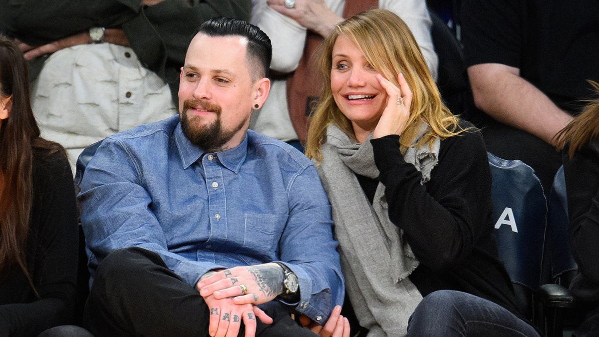 Benji Madden sitting courtside at a basketball game with Cameron Diaz