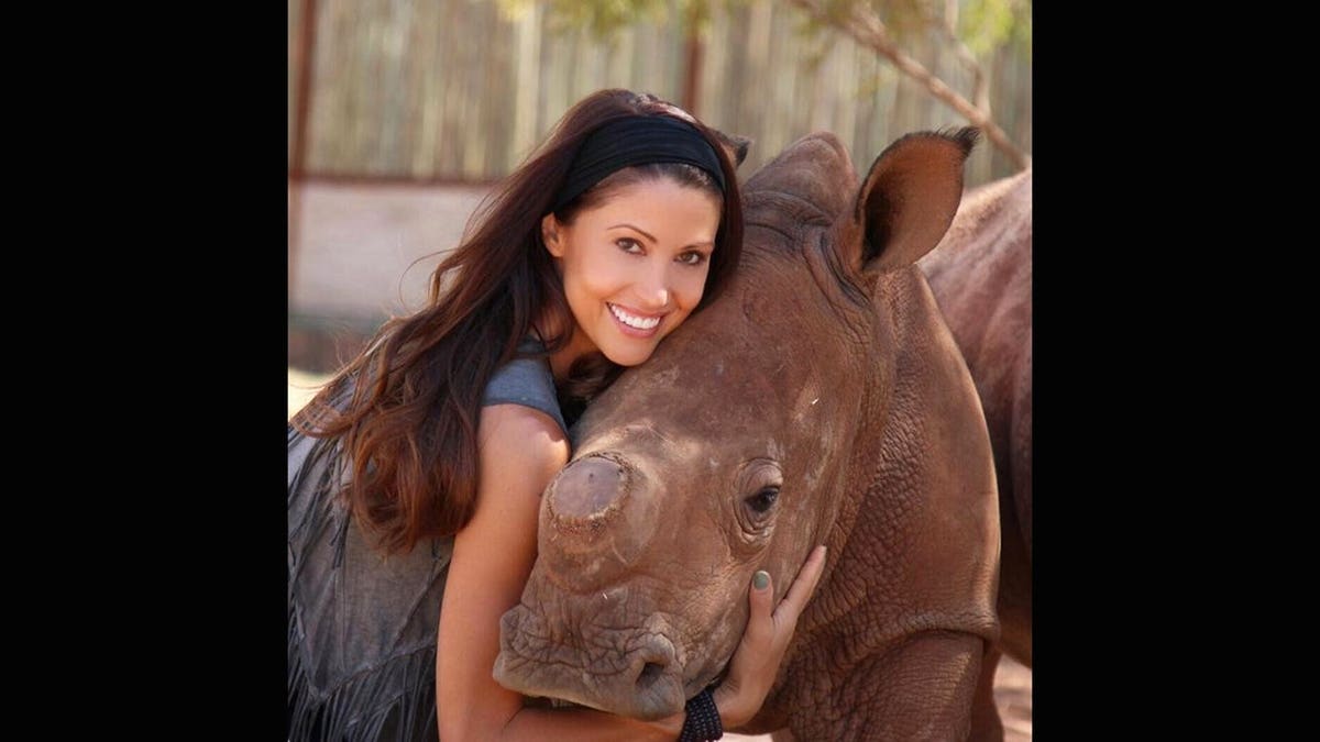 Shannon Elizabeth smiling and hugging a rhino.