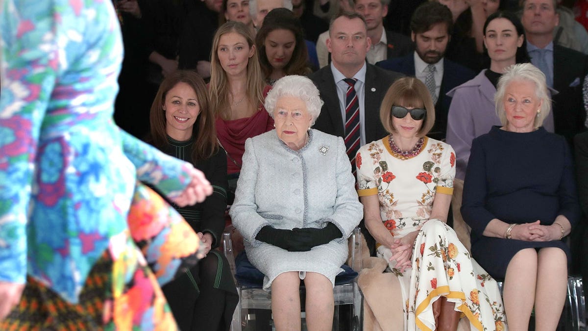 Queen Elizabeth II seated with Anna Wintour, Caroline Rush, and Angela Kelly at Richard Quinn runway show