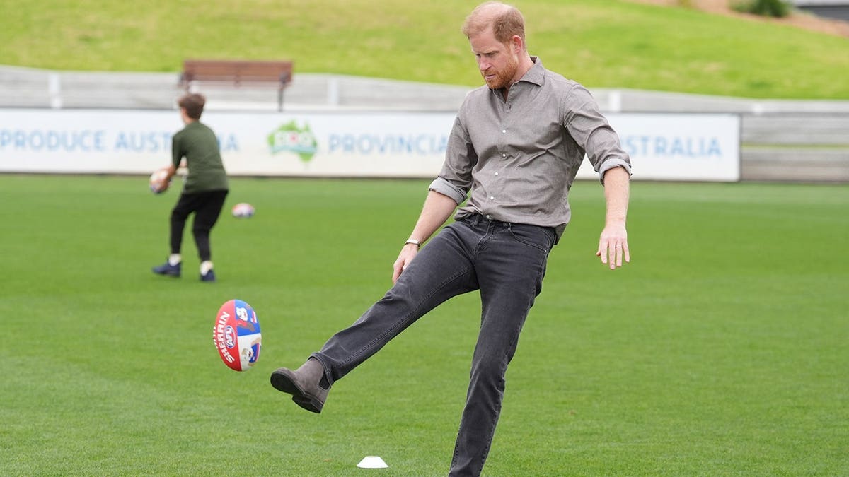 Prince Harry kicking a sherrin ball during Australian rules football session