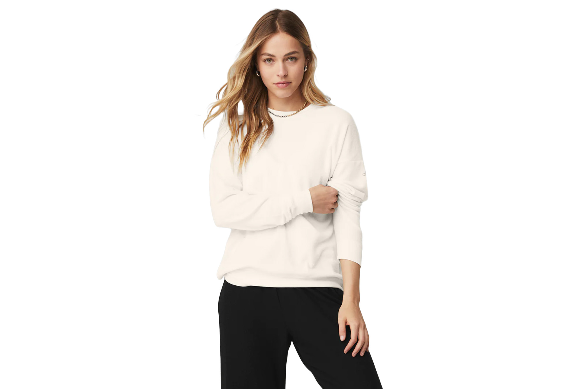A model in a cream-colored pullover and black joggers