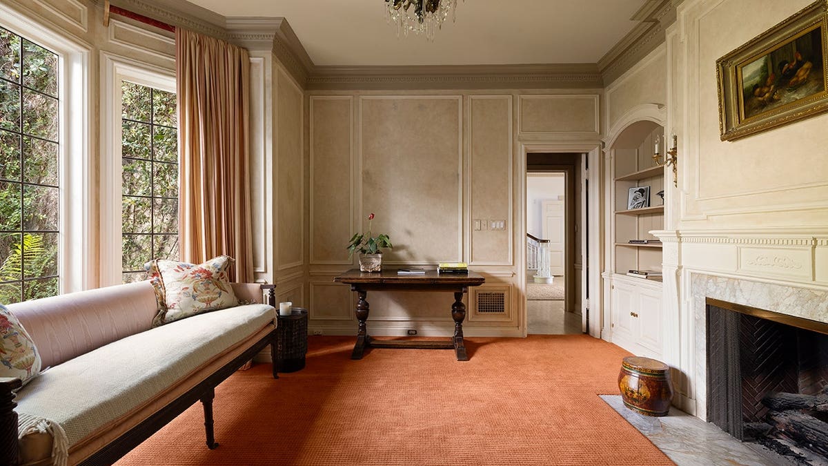 A room with a big window, a couch and a fireplace.