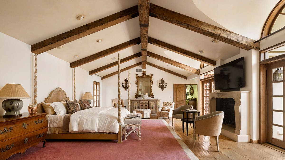 A bedroom with wooden beams and a juliet balcony