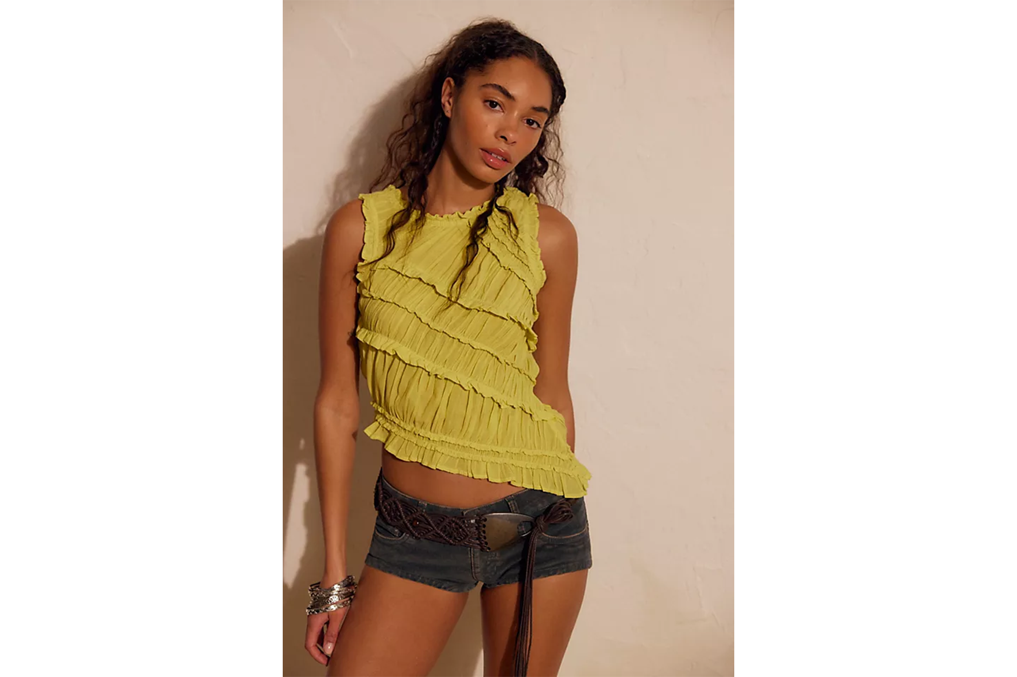 Model wearing a lime green sleeveless top with ruffles, denim shorts, and a dark brown belt.