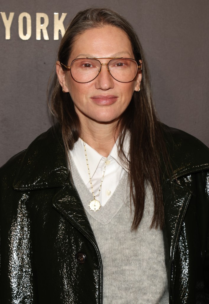 Jenna Lyons in glasses and dark green patent leather coat.