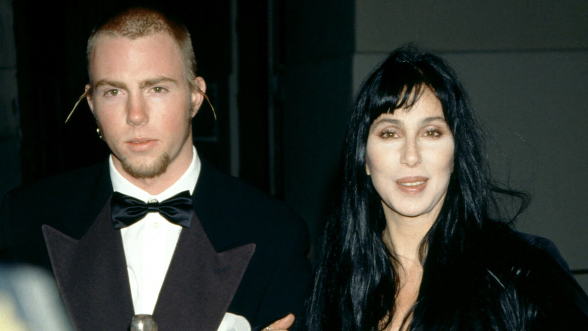 Cher and Elijah Blue Allman walking on a red carpet at an awards show.