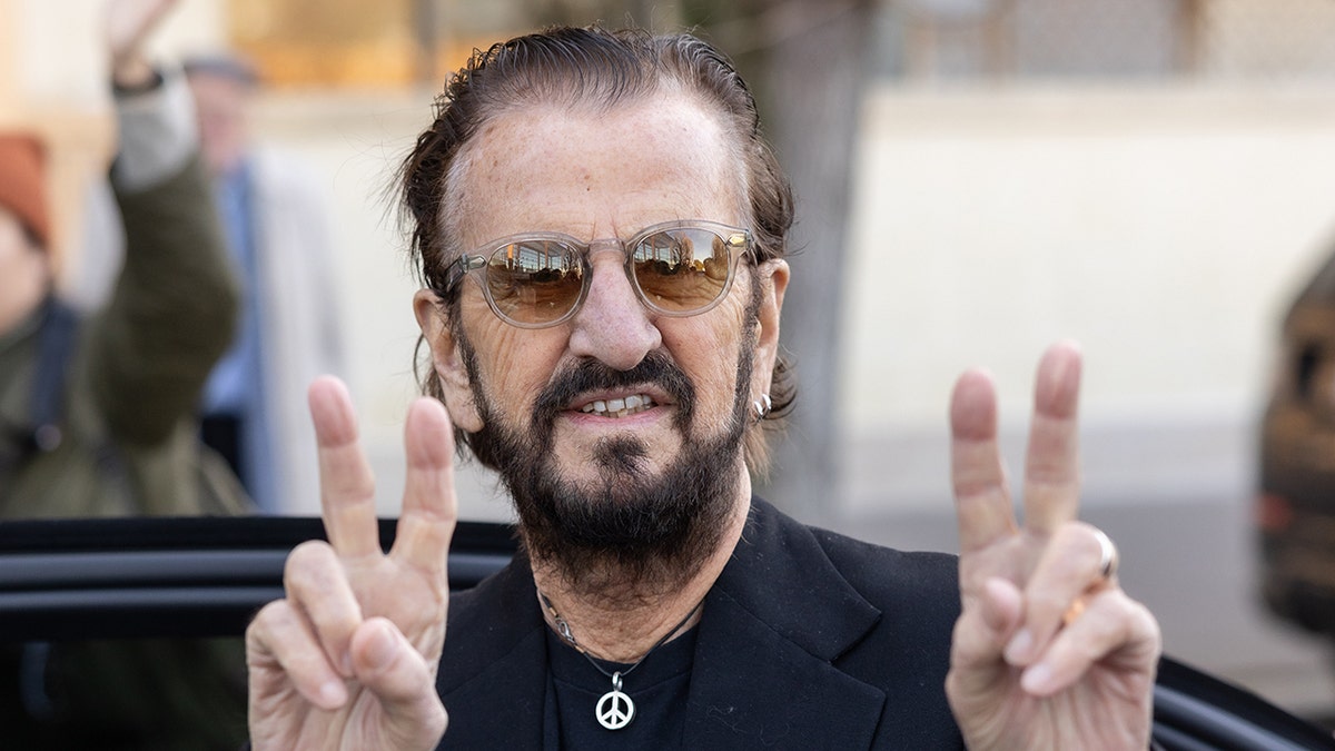 Ringo Starr flashing peace signs at Paris Fashion Week