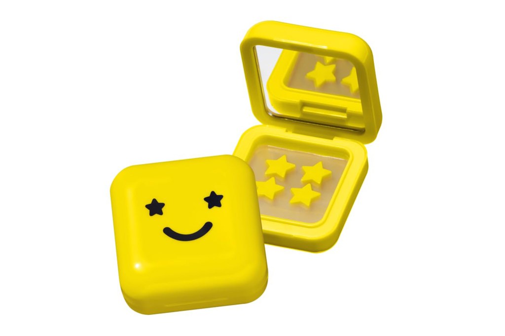 A yellow rectangular compact with a smiley face on the lid and four yellow star-shaped patches inside.