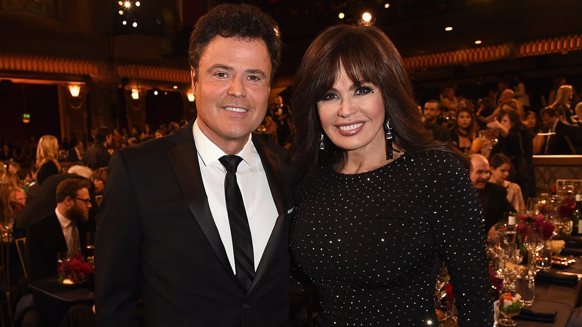 donny and marie osmond smile and pose together at an event